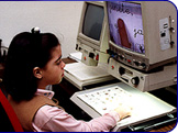 Ni&ntilde;a con deficiencia visual ante un monitor.